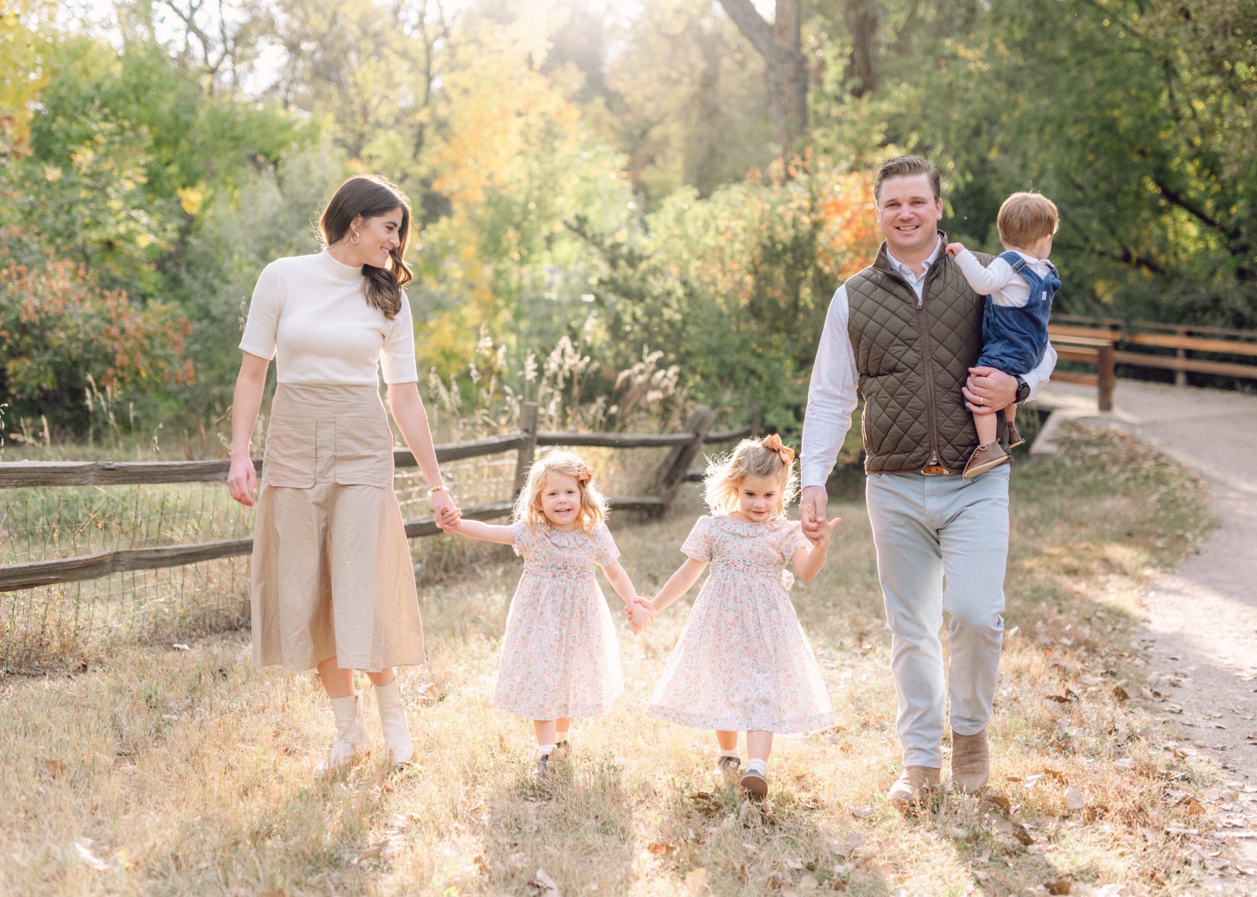 Family of five walking holding hands on a golden fall day smiling and laughing with each other