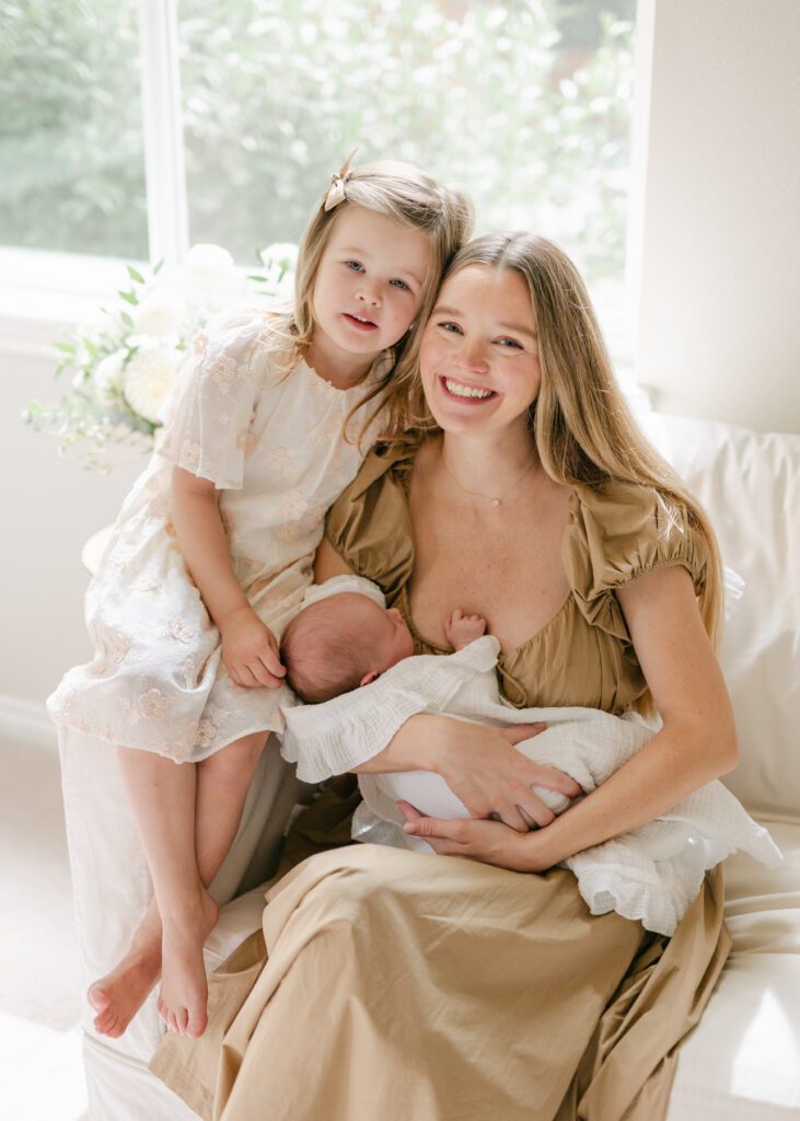 Mom smiling with her two daughters in a classic white elegant room. Photo by Denver photographer Maegan R Photography