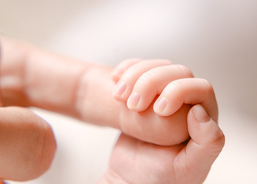 Close up image of a baby's hand holding a pointer finger. Photograph by Maegan R Photography. 